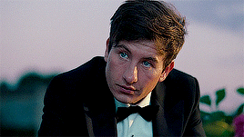 Barry Keoghan wearing a formal suit with a bow tie, looking thoughtful in an outdoor setting