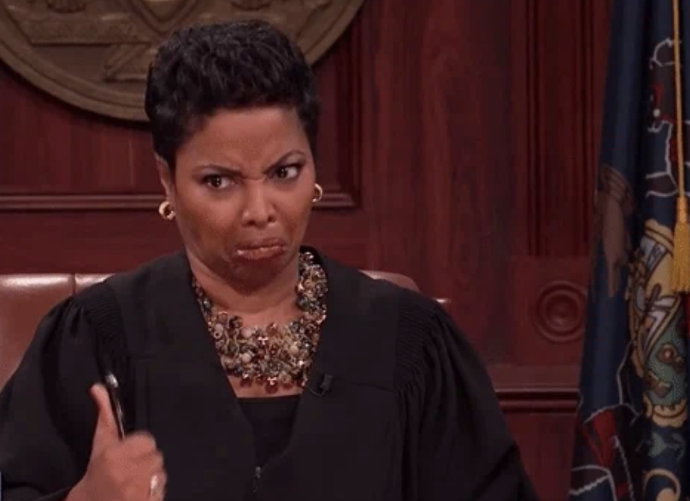Judge Judy making a skeptical face while listening to a case in her courtroom. She is wearing a judicial robe and a statement necklace