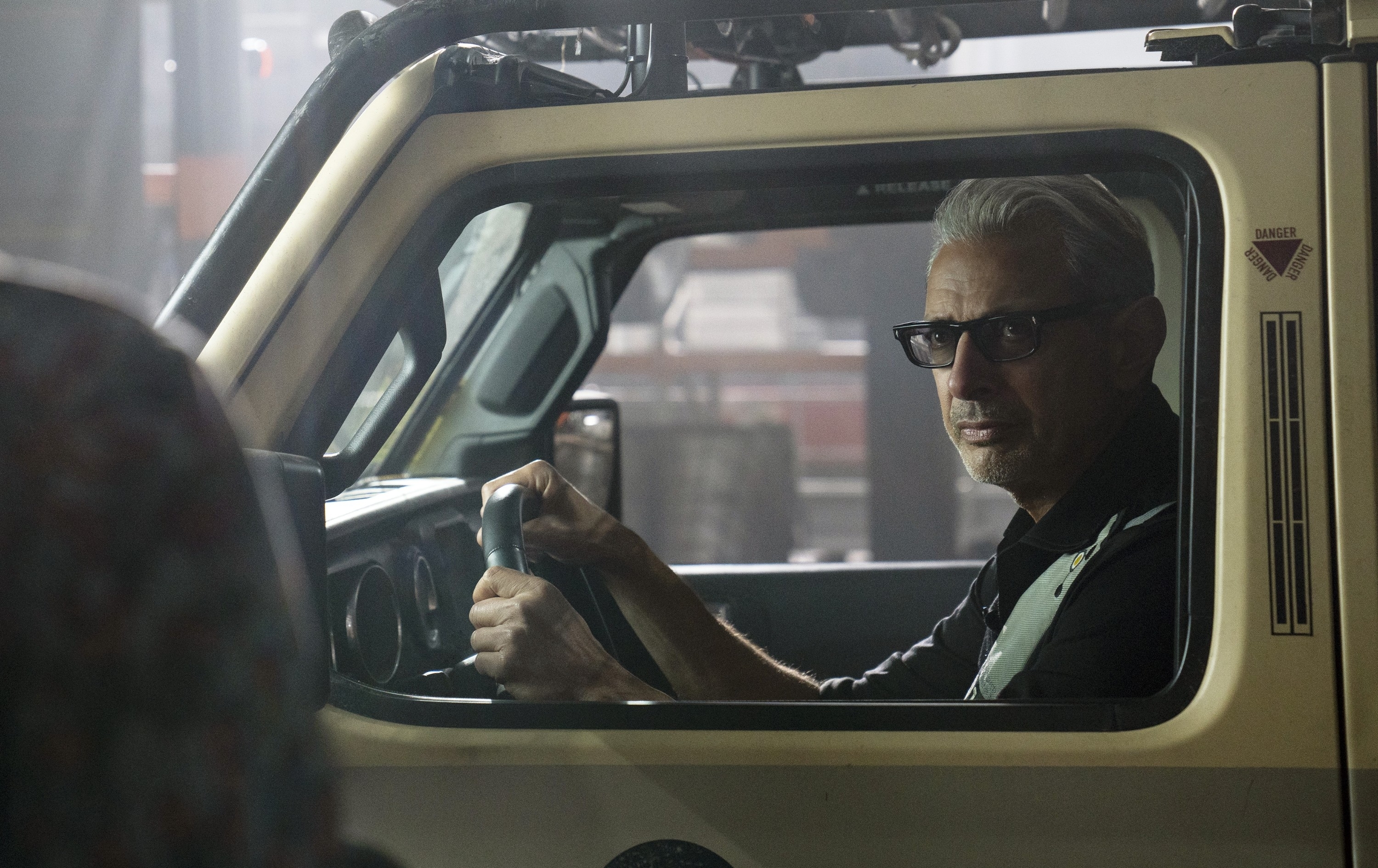 Jeff Goldblum sitting in the driver's seat of a car in "Jurassic World Dominion"