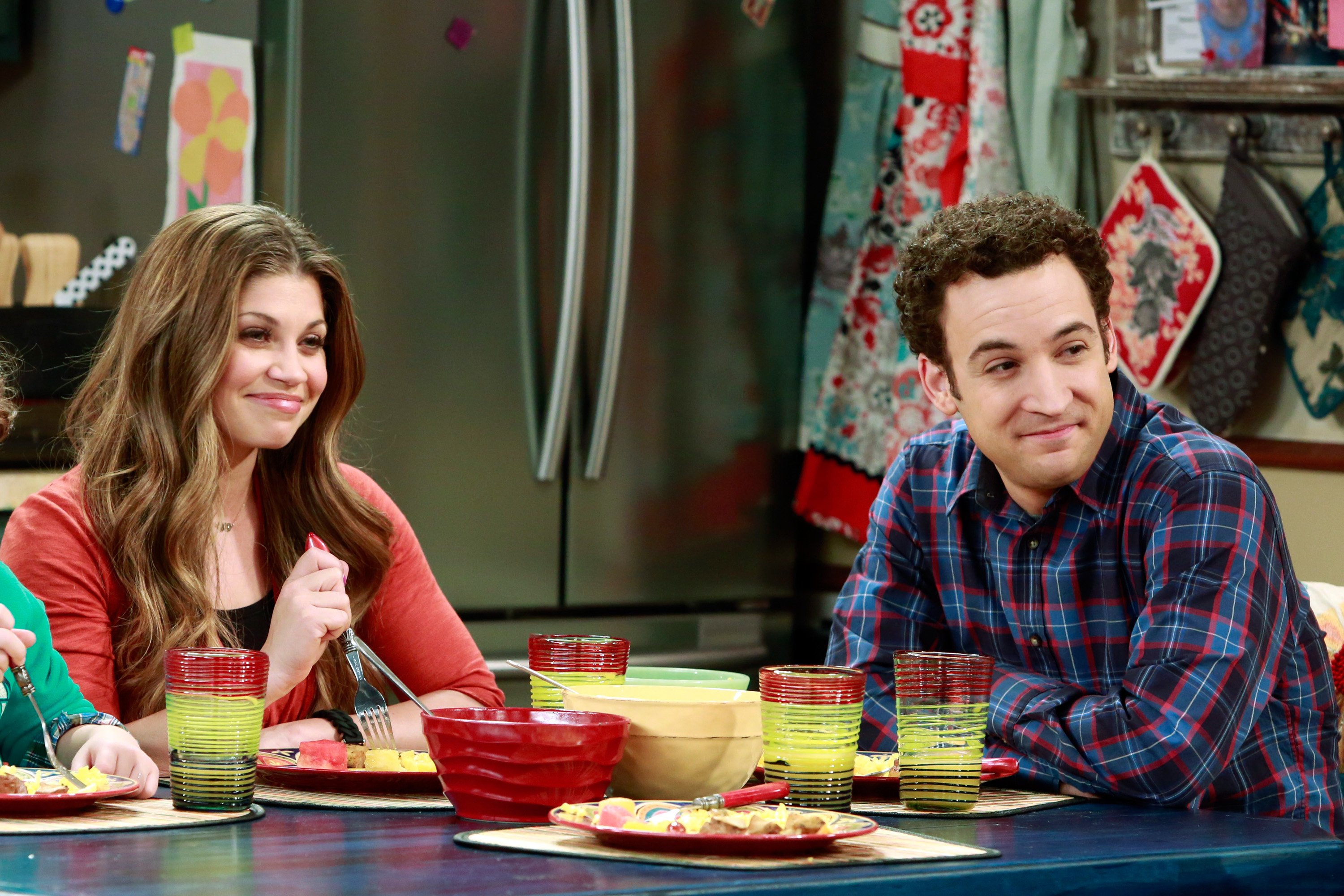 Danielle Fishel and Ben Savage sitting at a kitchen table with tableware in front of them in "Girl Meets World"