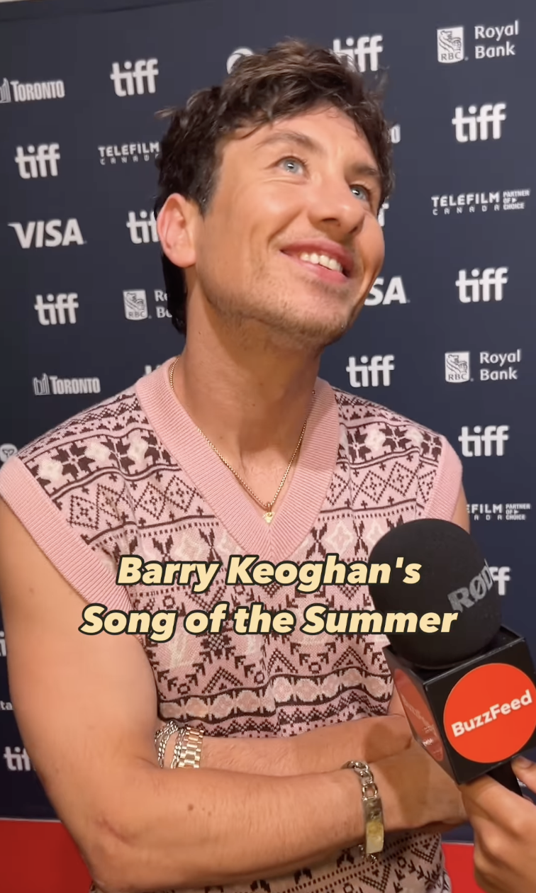 Barry Keoghan smiles during an interview on the TIFF red carpet, wearing a patterned sleeveless sweater. A BuzzFeed microphone is visible. Text reads: "Barry Keoghan's Song of the Summer."