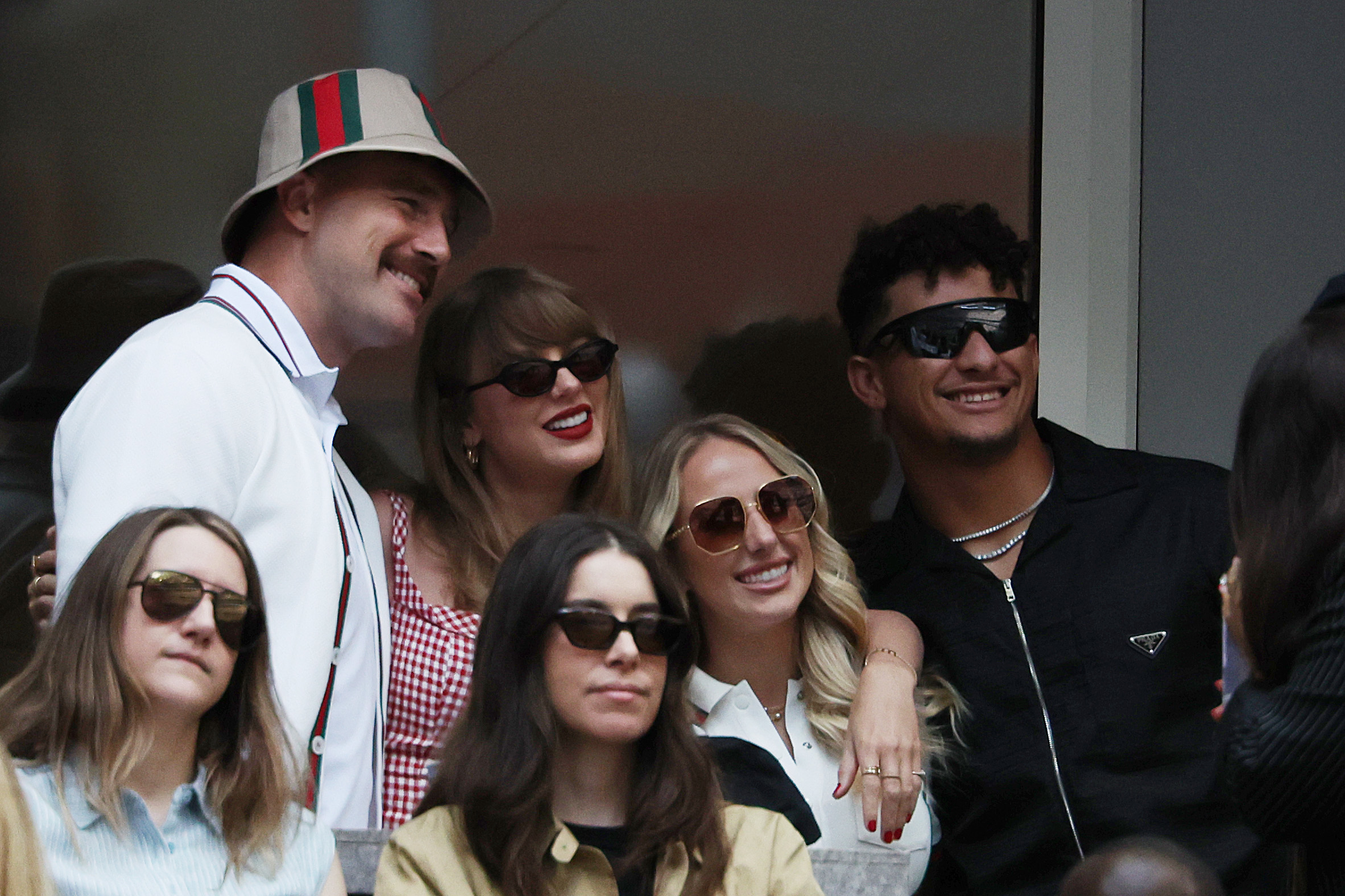 Travis Kelce, Taylor Swift, Brittany Mahomes, and Patrick Mahomes smile and pose together; all wear sunglasses and casual outfits