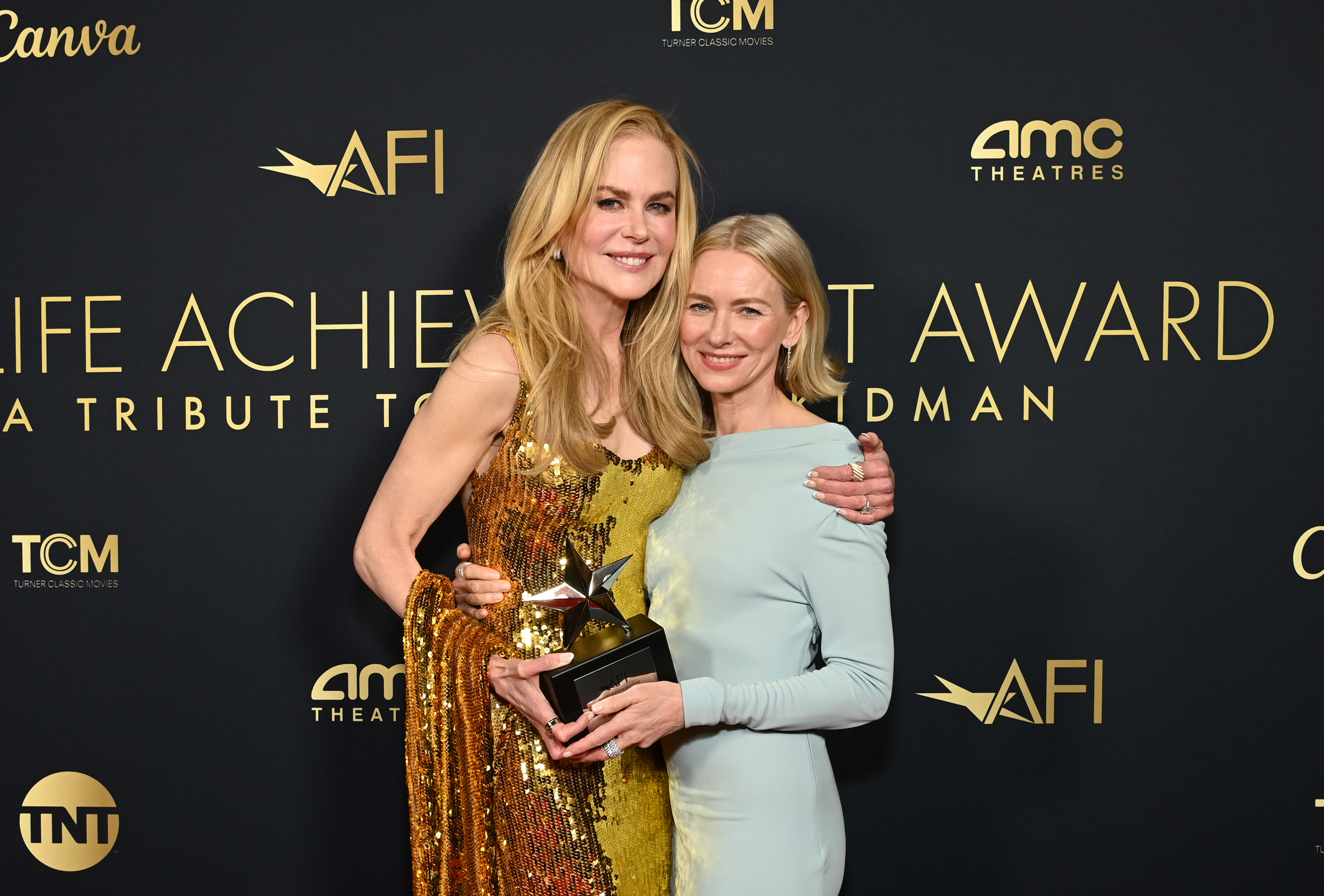 Nicole Kidman and Naomi Watts pose affectionately on the red carpet at the Life Achievement Award tribute, with Nicole holding a trophy