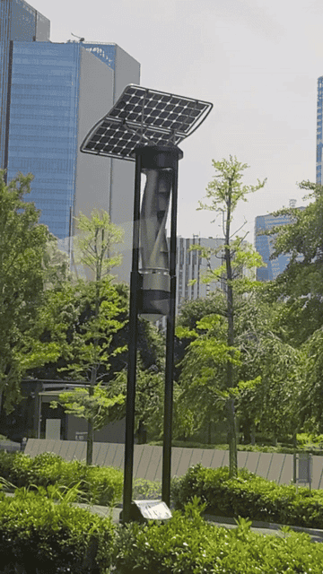 A tall solar panel light stands against a backdrop of city skyscrapers and lush greenery