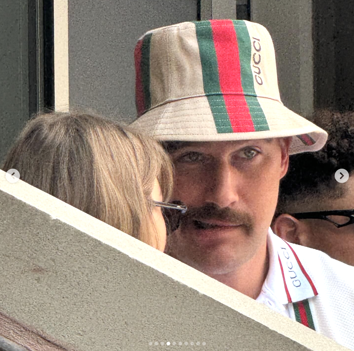 Phil Dunster wearing a Gucci bucket hat and talking to a person with glasses