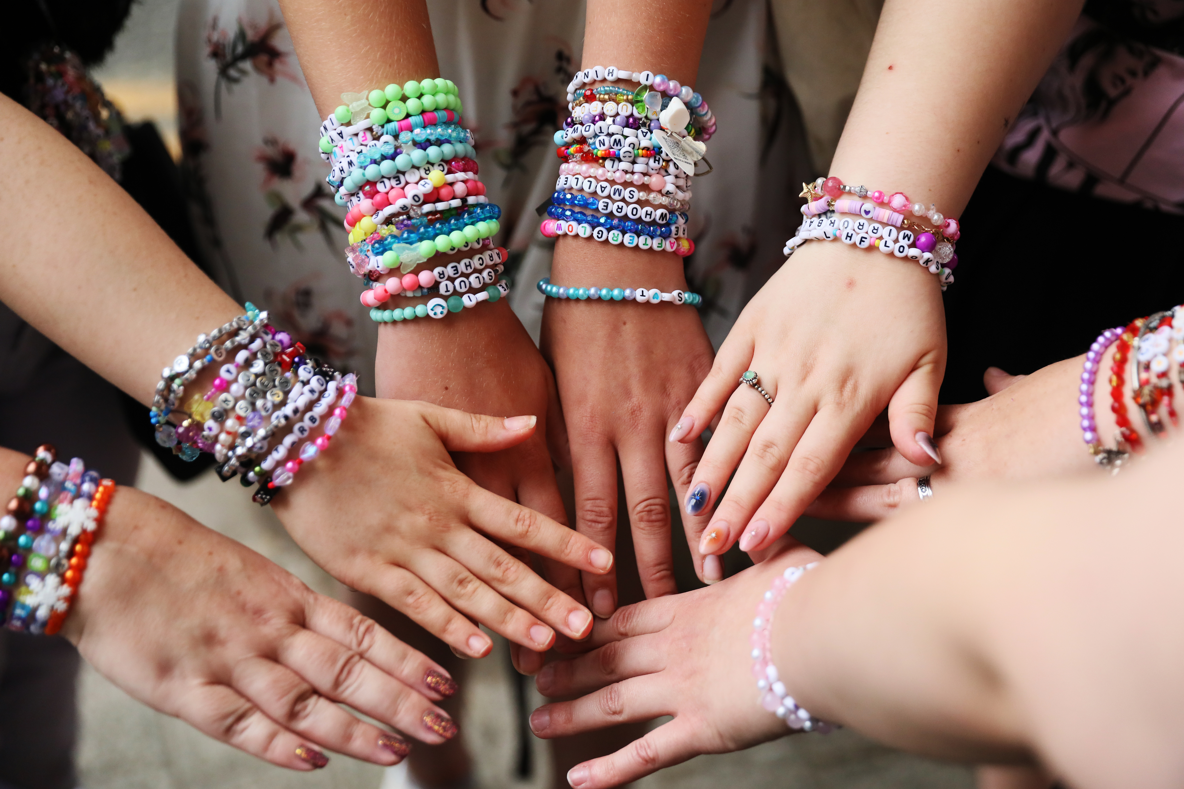 Taylor Swift fans showing off friendship bracelets with their hands in a circle at an Eras tour show