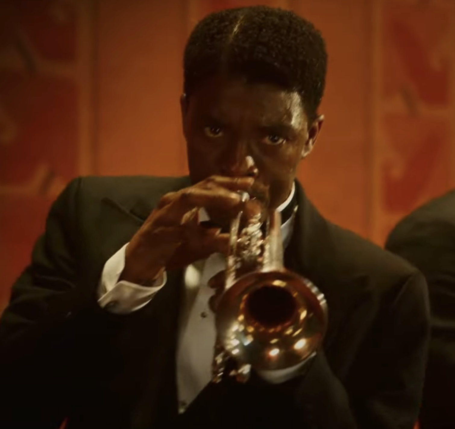 Chadwick Boseman playing the trumpet in a tuxedo