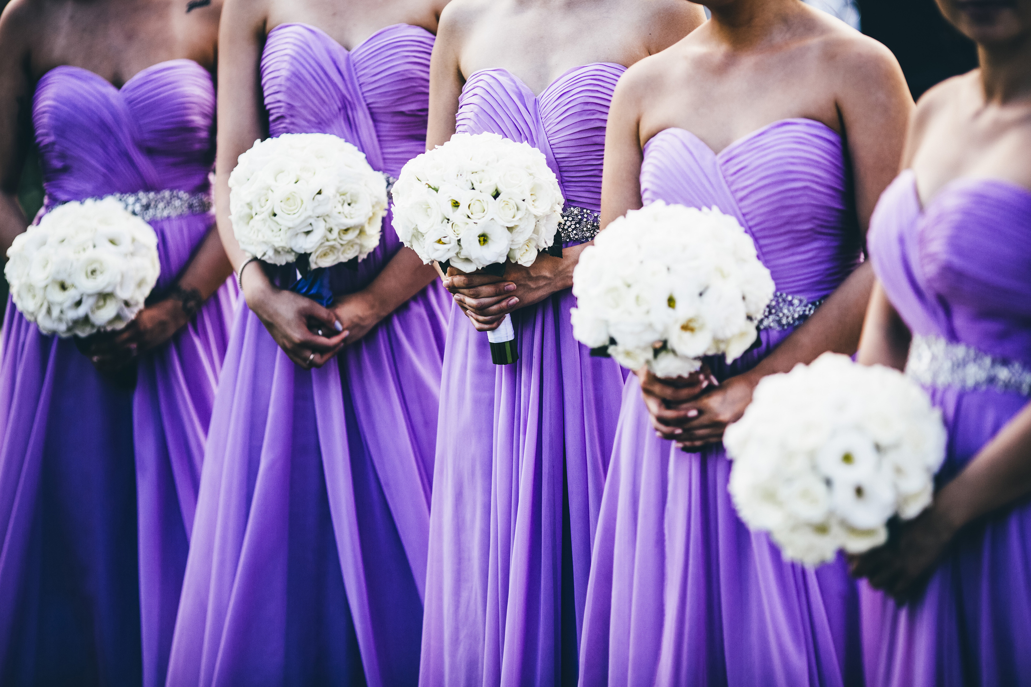 Bridesmaids in strapless dresses holding white flower bouquets at a wedding ceremony
