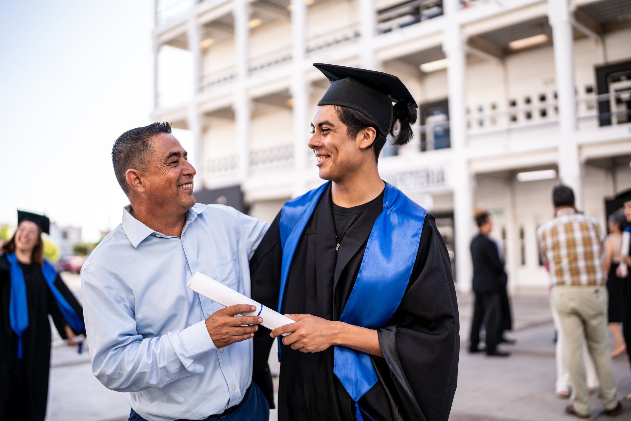 A father and college graduate son celebrate at a graduation ceremony