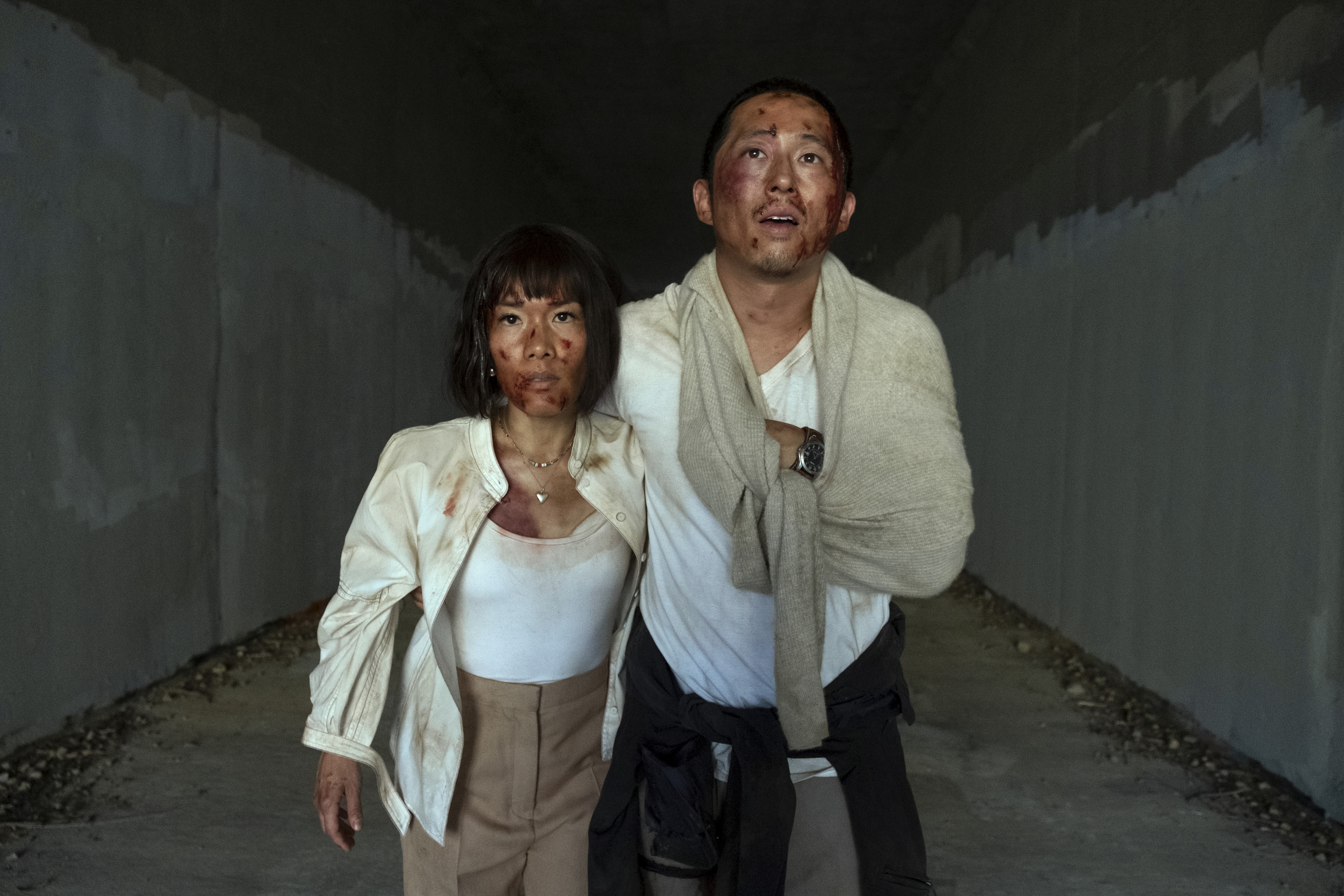 Ali Wong and Steven Yeun, characters in "Beef", stand in a tunnel with dirt-streaked faces and clothing, appearing exhausted but determined