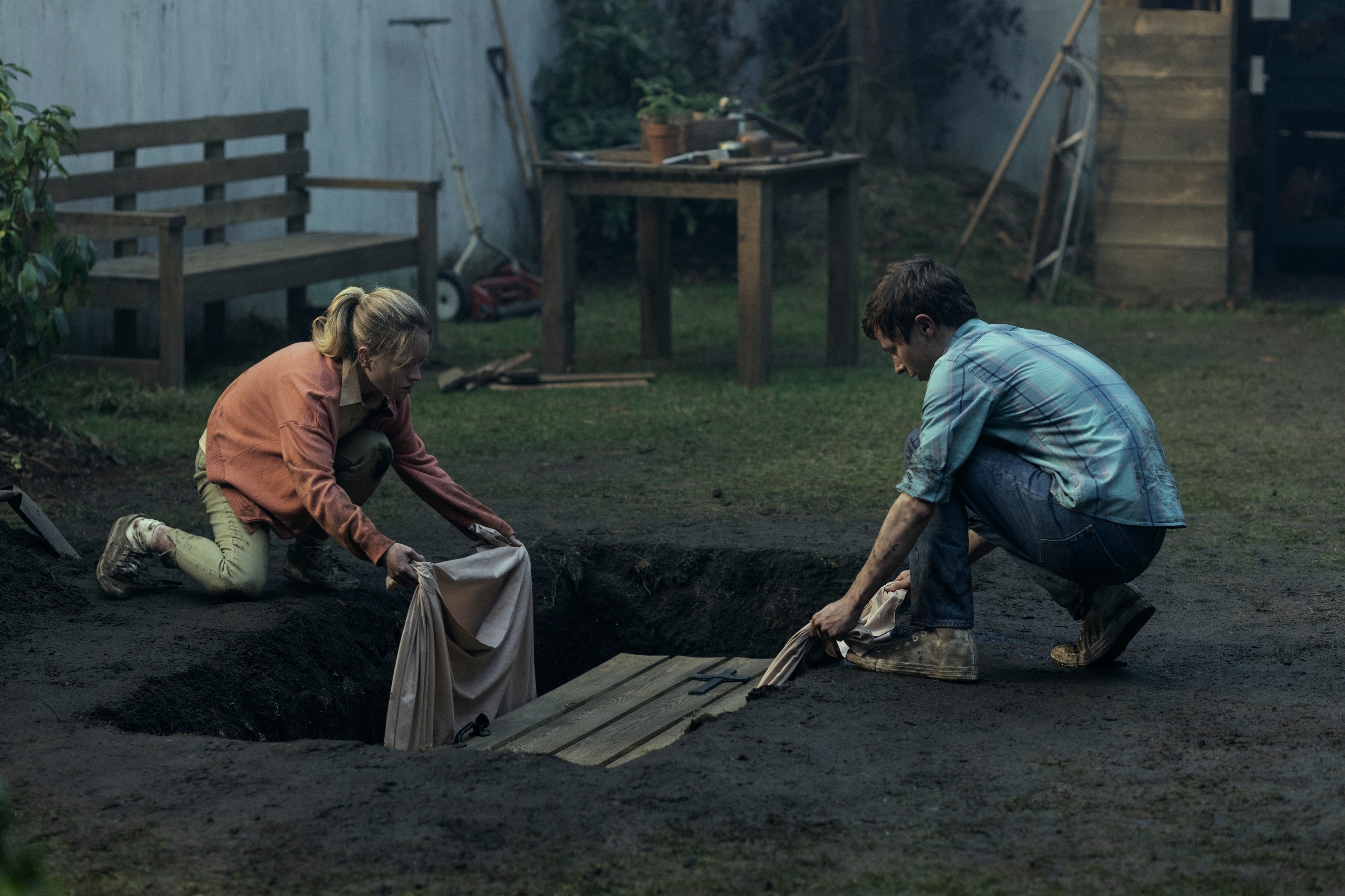 Carrie Coon and Paul Rudd in a yard digging and preparing a wooden structure in a hole