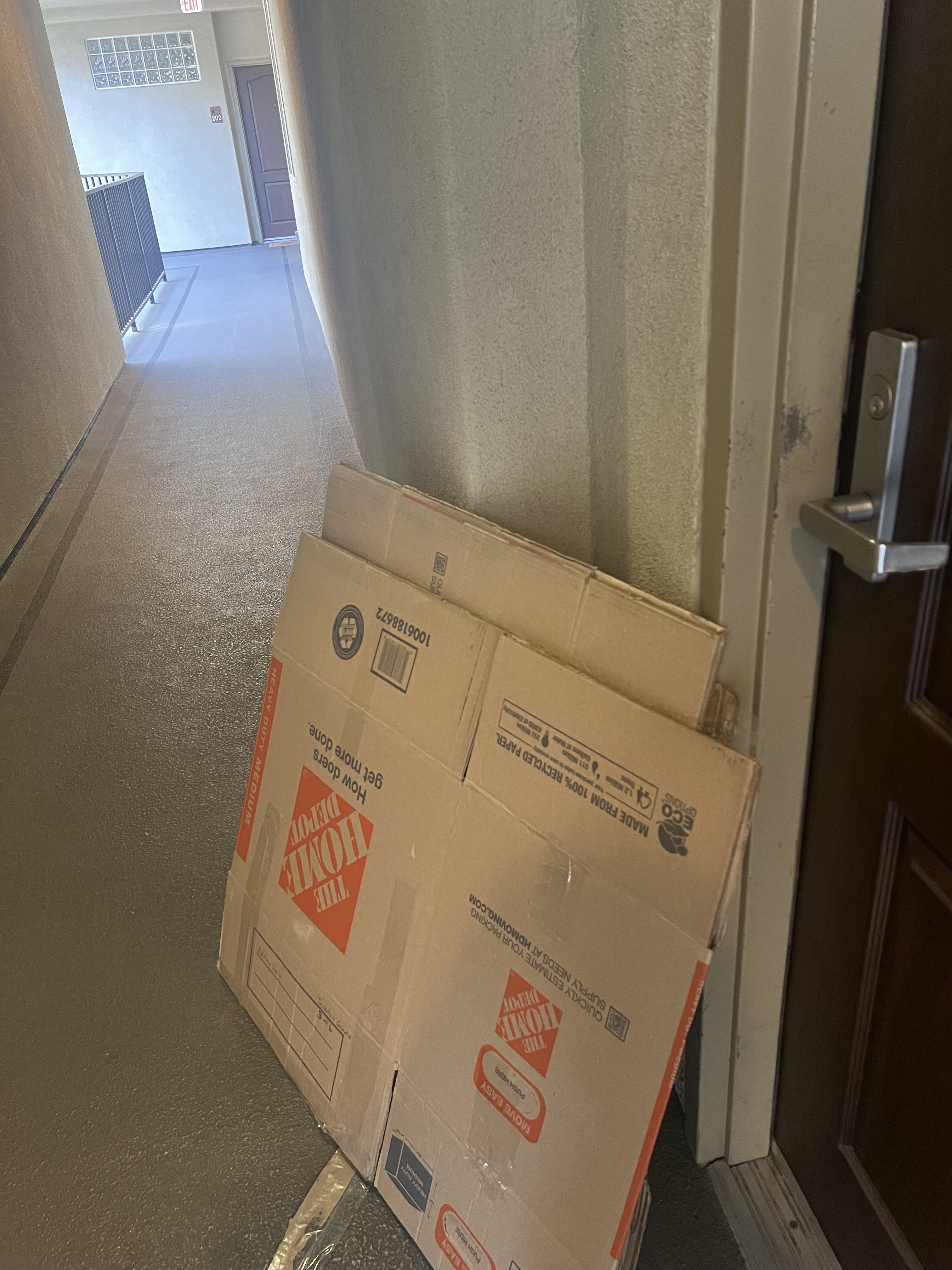 Stack of flattened cardboard moving boxes leaning against a hallway wall near a door