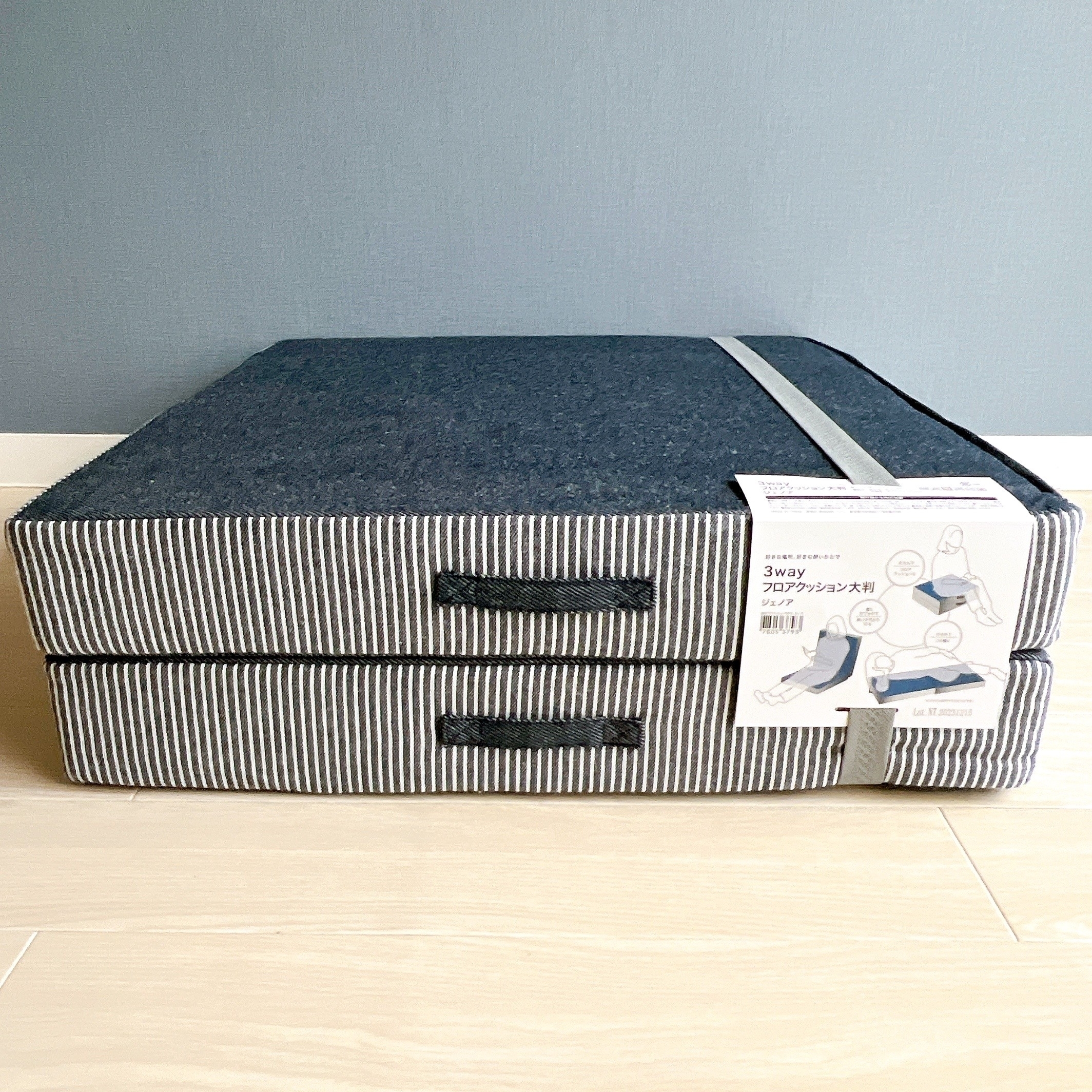 2枚重ねの灰色と白のストライプのクッション。タグには3way折りたたみクッションと書かれています。