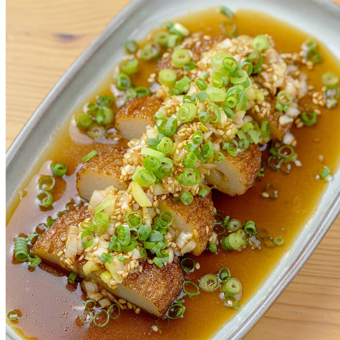 皿に盛られたさつま揚げ料理で、たっぷりのネギソースが上にのせられています。