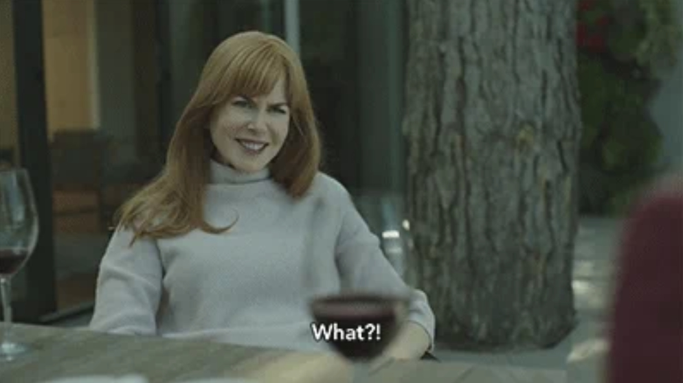 Nicole Kidman, sitting at a table outside, looks surprised. A wine glass is in front of her, and the caption reads, "What?!"