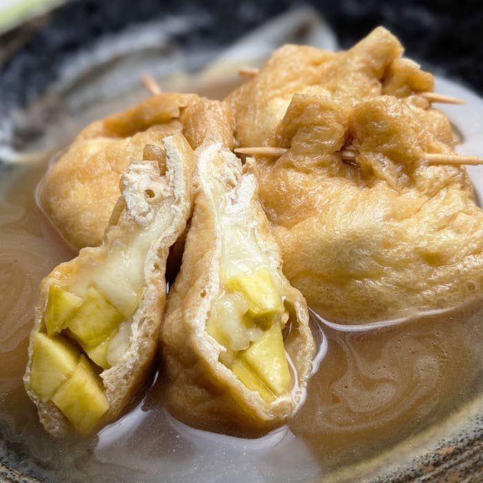 煮物料理のクローズアップ写真。油揚げの中に具が詰められている。