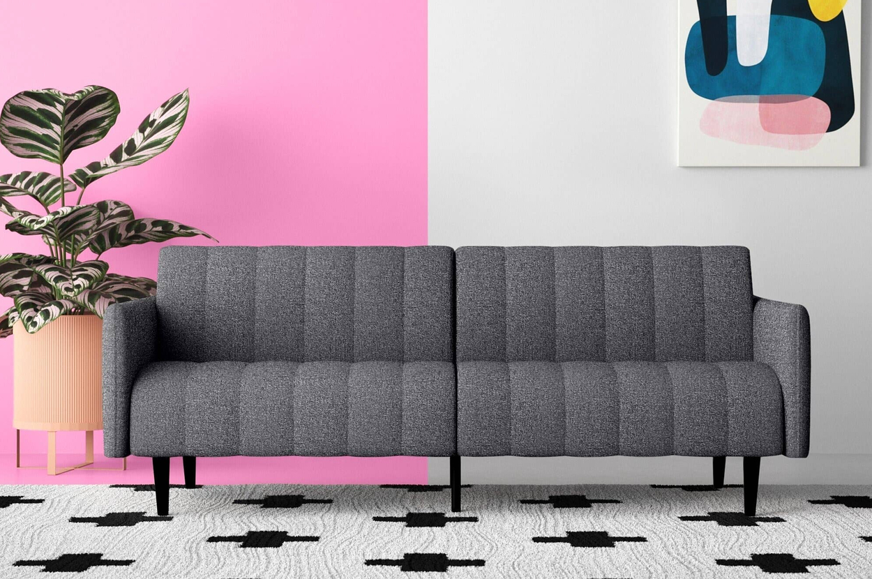 Modern gray sofa on a patterned rug with a potted plant and abstract artwork in the background