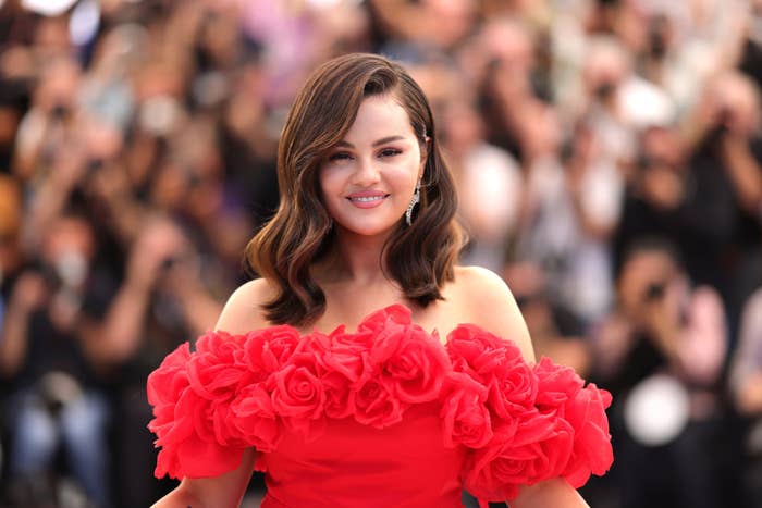 Selena Gomez poses on the red carpet in an off-the-shoulder dress adorned with large floral details