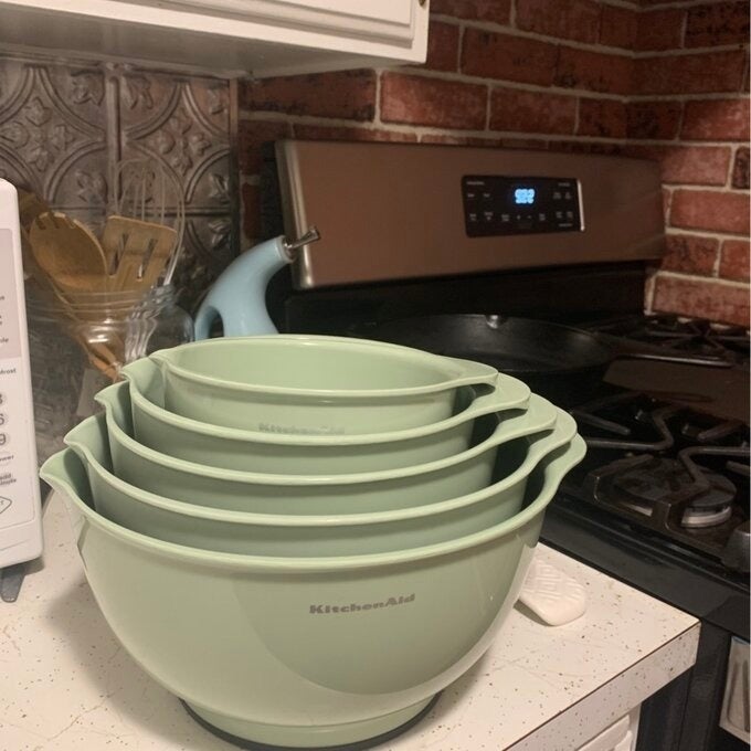 Stacked KitchenAid mixing bowls connected  a room  antagonistic  adjacent   a stove and a toaster