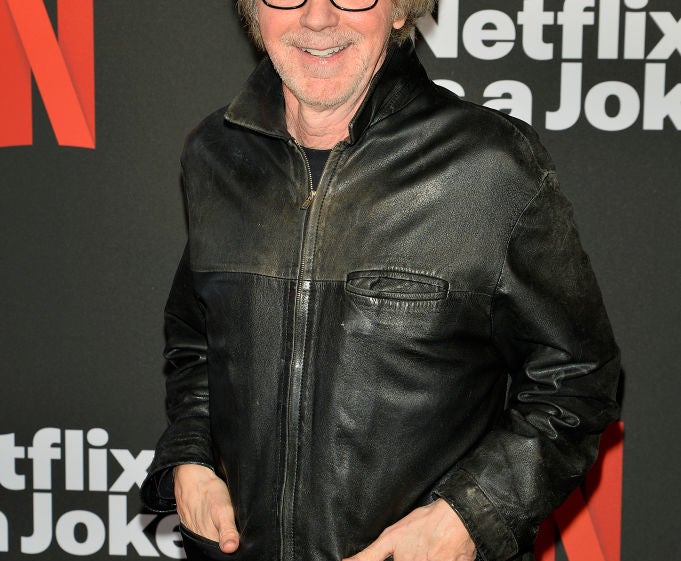 Man in a leather jacket poses at a Netflix event backdrop