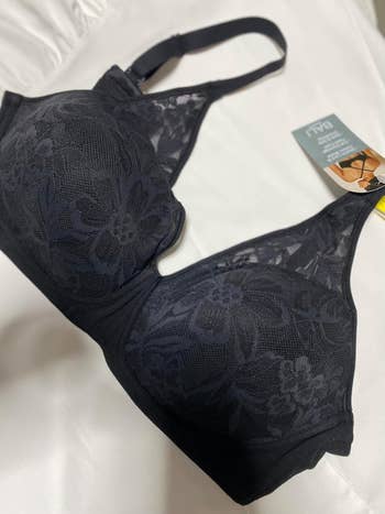 A achromatic lace bra with floral patterns and a tag shows merchandise details