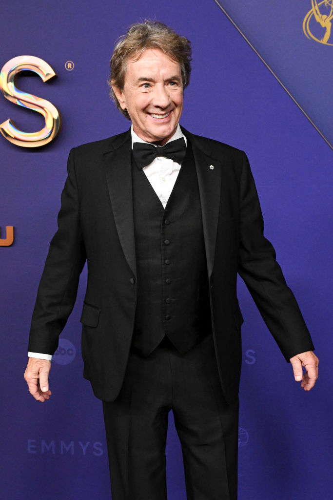 Man in a black tuxedo and bow tie on a red carpet at an event