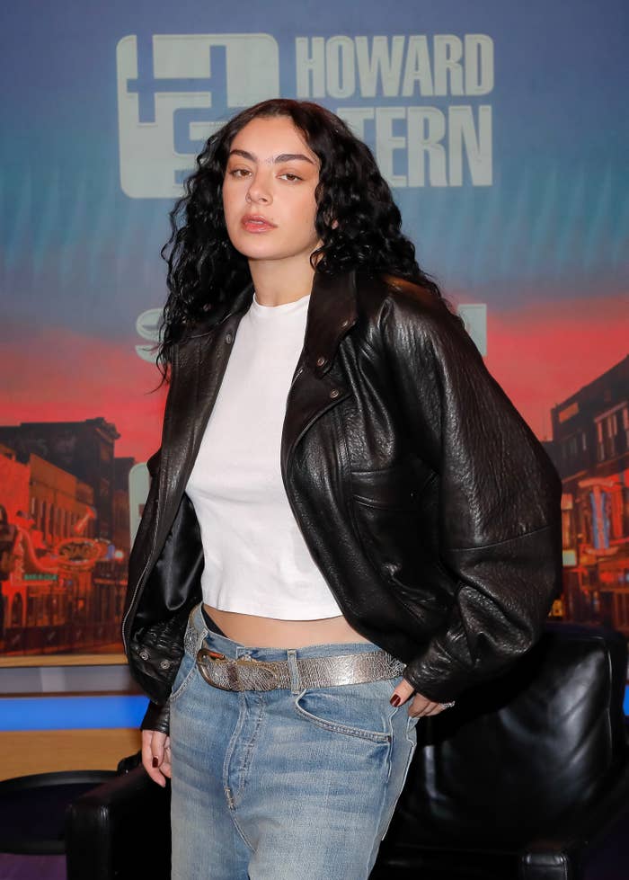 Charli XCX in jeans, a white shirt, and a leather jacket