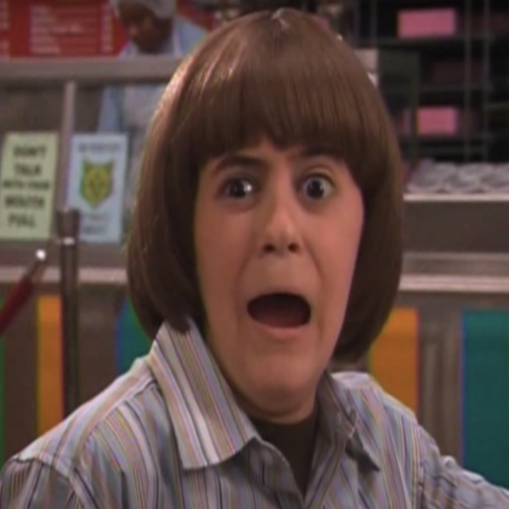 A surprised child in a striped shirt, with a bob haircut, reacts dramatically in a diner setting