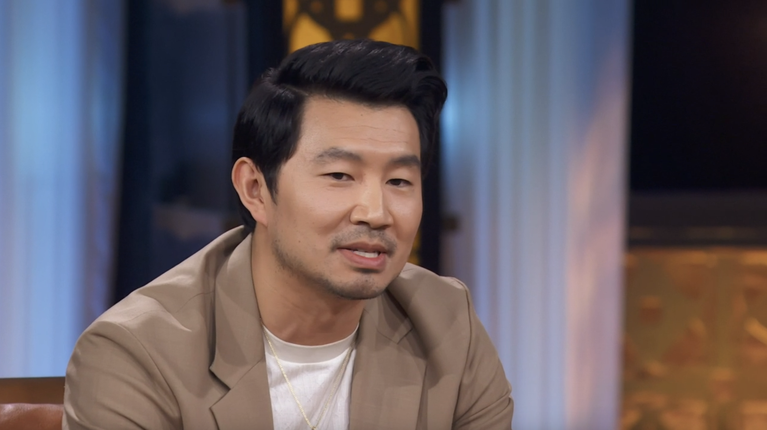 Simu Liu sits in a chair, talking