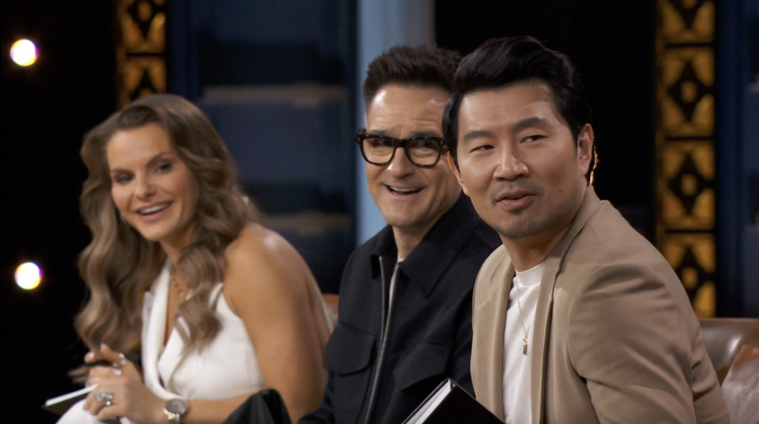 Individuals are sitting together, smiling, dressed in formal attire