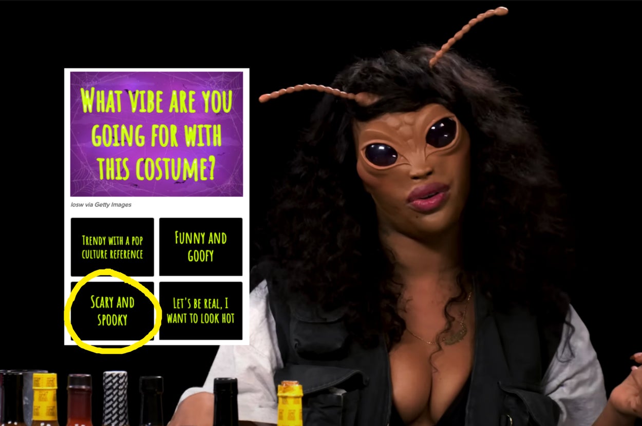 A person wearing an elaborate insect-themed mask with antennae and large black eyes is talking or posing for the camera