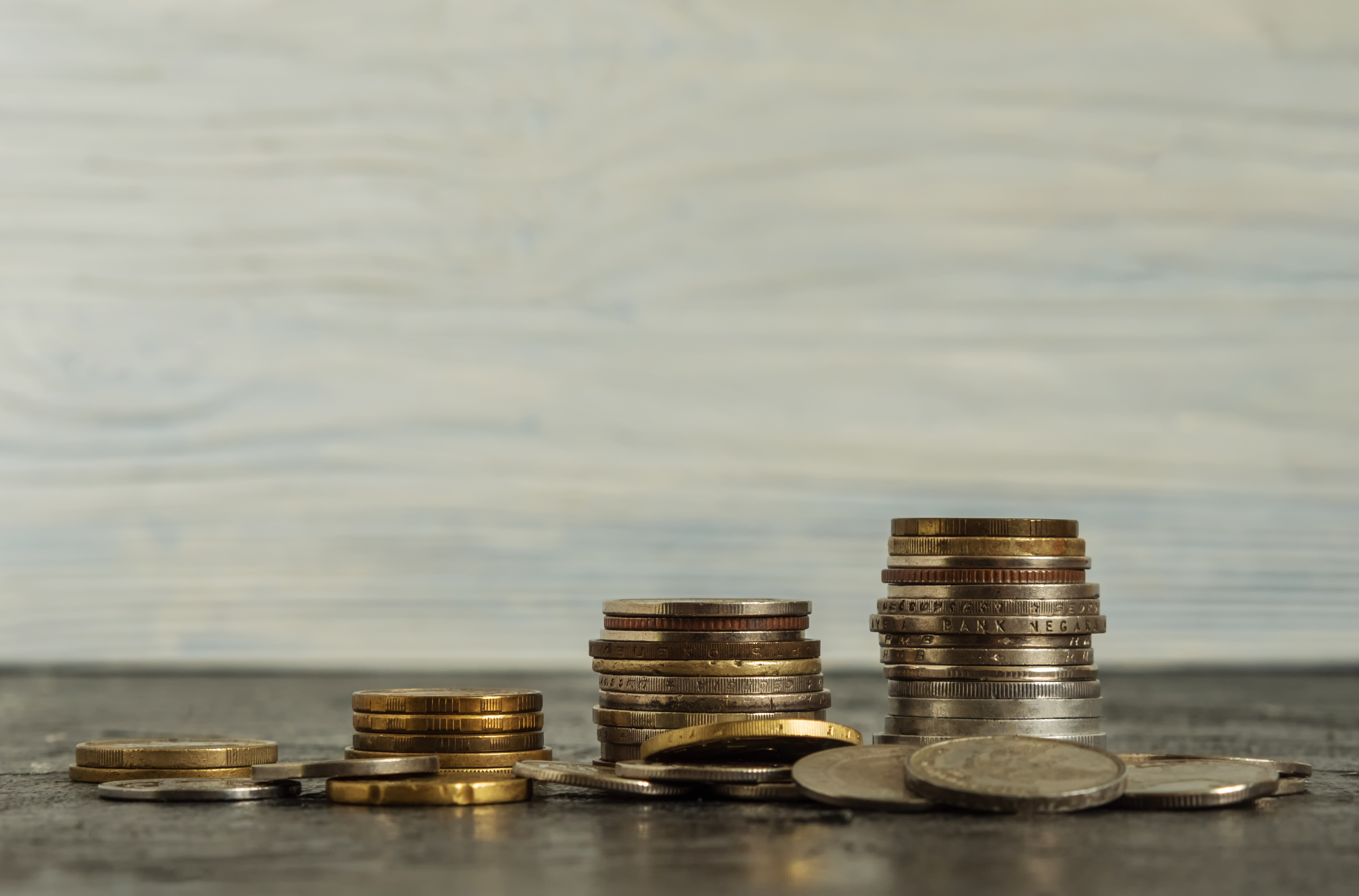 Stacks of assorted coins on a flat surface against a neutral background