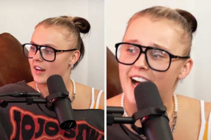 Person wearing glasses and a necklace, speaking into a microphone during a podcast