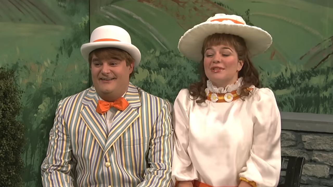 Two people in vintage, striped attire with hats, sitting together and smiling in a theater setting