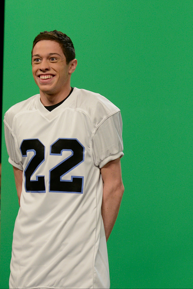 Person in a white sports jersey with number 22, smiling against a green screen