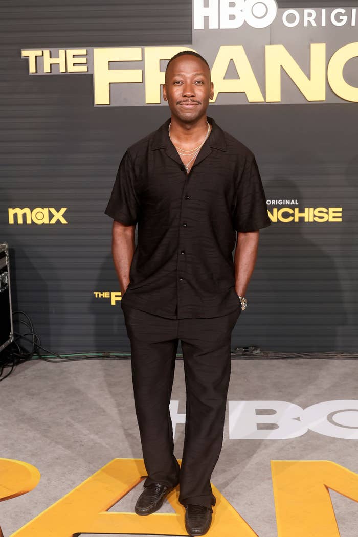 Man in a black casual outfit standing on a red carpet at an HBO event backdrop