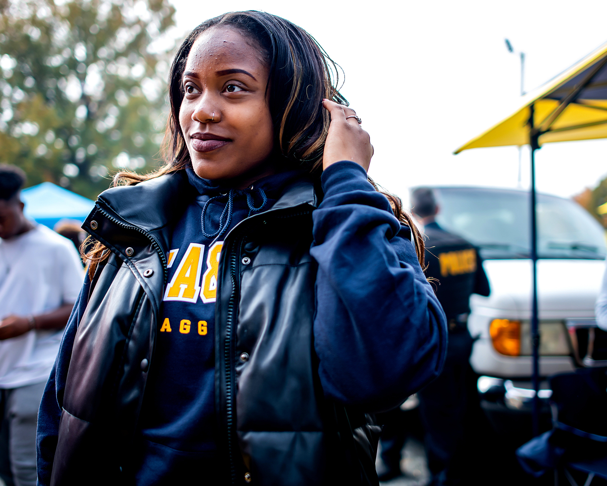 En person iført svart vest og genser står utendørs på noe som ser ut til å være en uformell sammenkomst