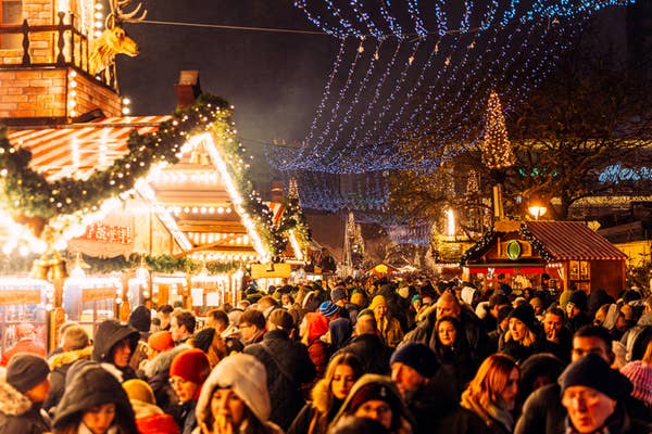 Crowded night Christmas market with festive lights, bustling with people enjoying the holiday atmosphere