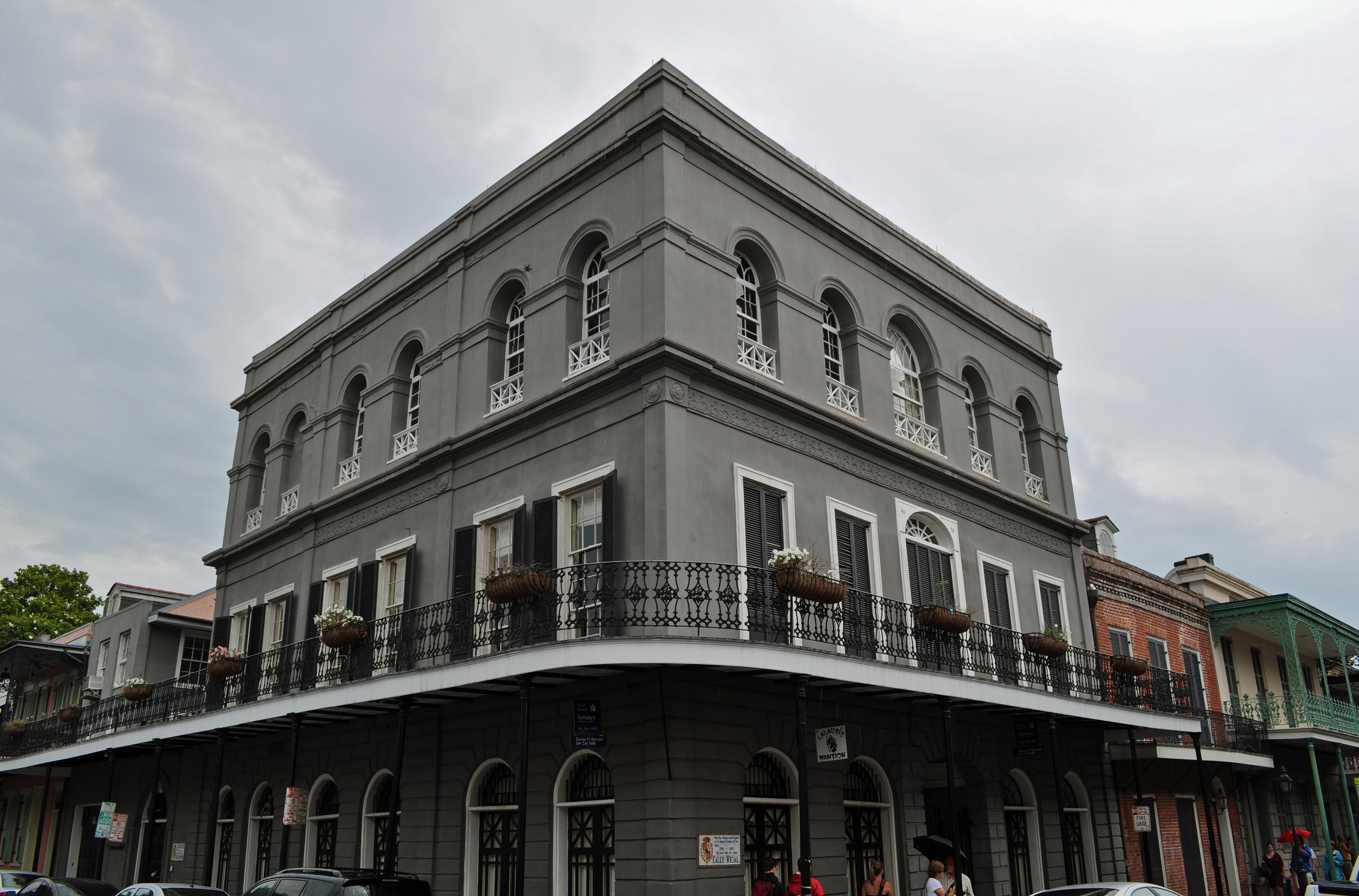 Historic building on a corner in New Orleans features arched windows and ornamental iron balconies