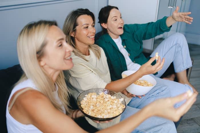 Three women sitting on a couch enjoying a movie or show together