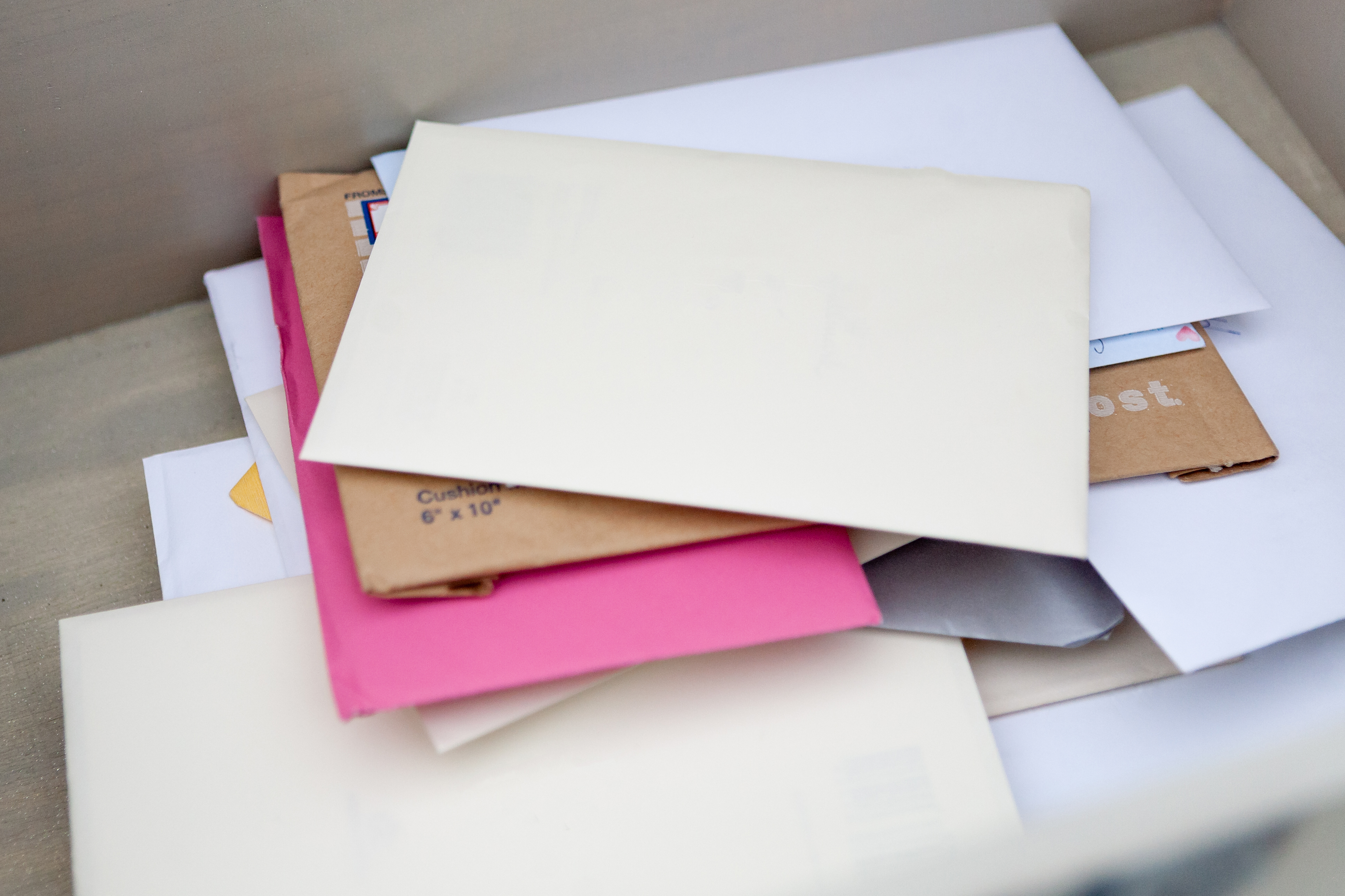 A pile of assorted envelopes, some plain and some colored, stacked on a surface