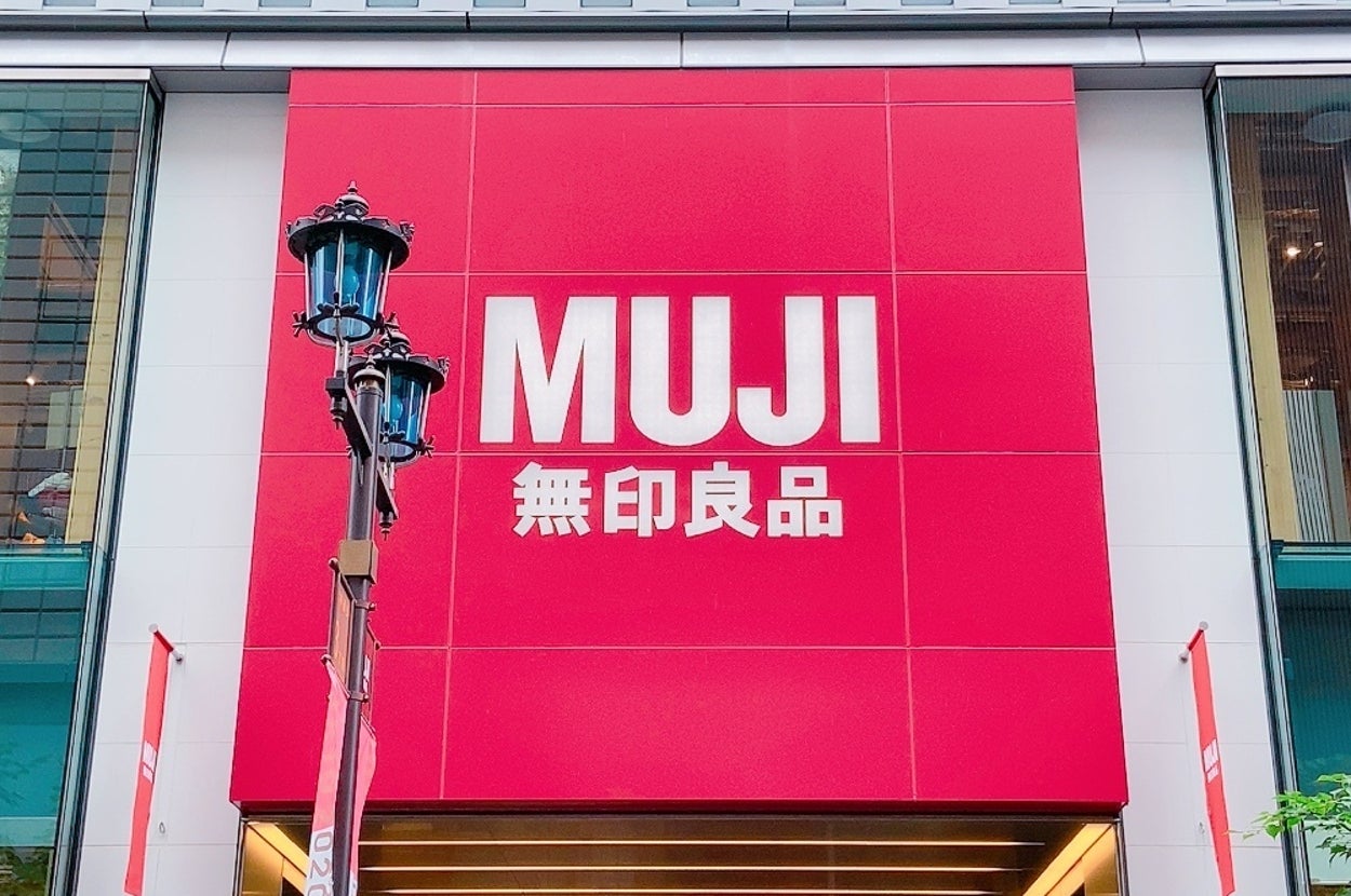 MUJIの店舗外観。大きな赤い看板に「MUJI 無印良品」と書かれています。