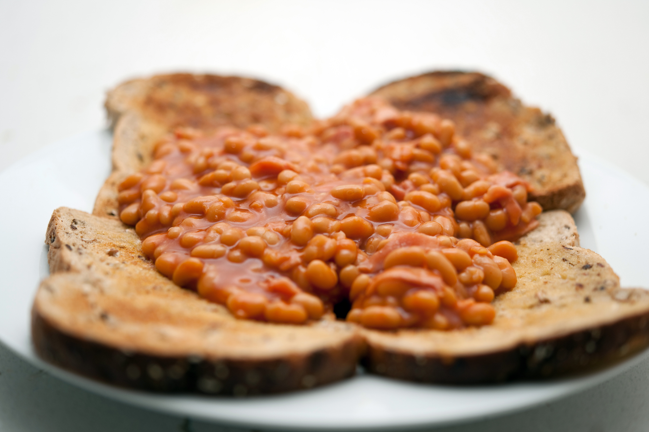 Baked beans on five slices of toast, arranged on a white plate