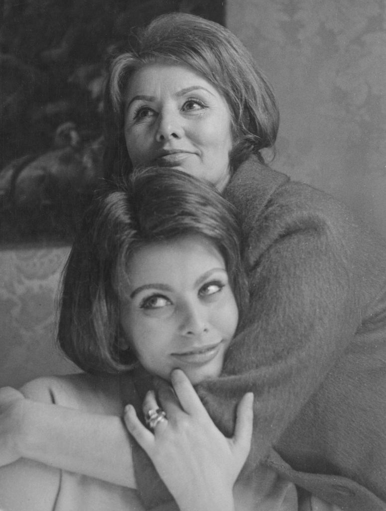 Romilda embracing Sophia and resting her chin on her head. Both are dressed elegantly and have bob haircuts