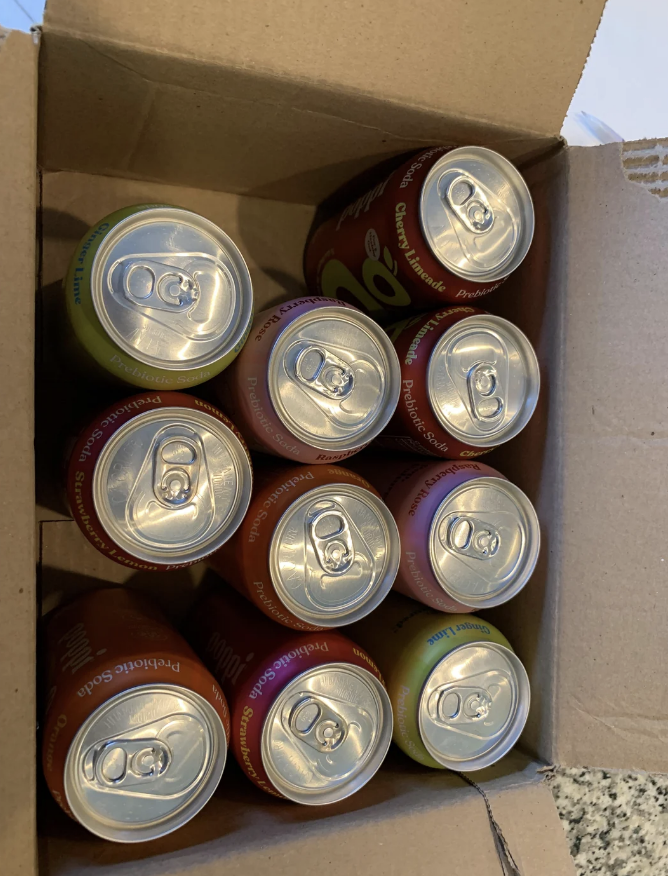 A box containing 12 unopened soda cans is viewed from the top