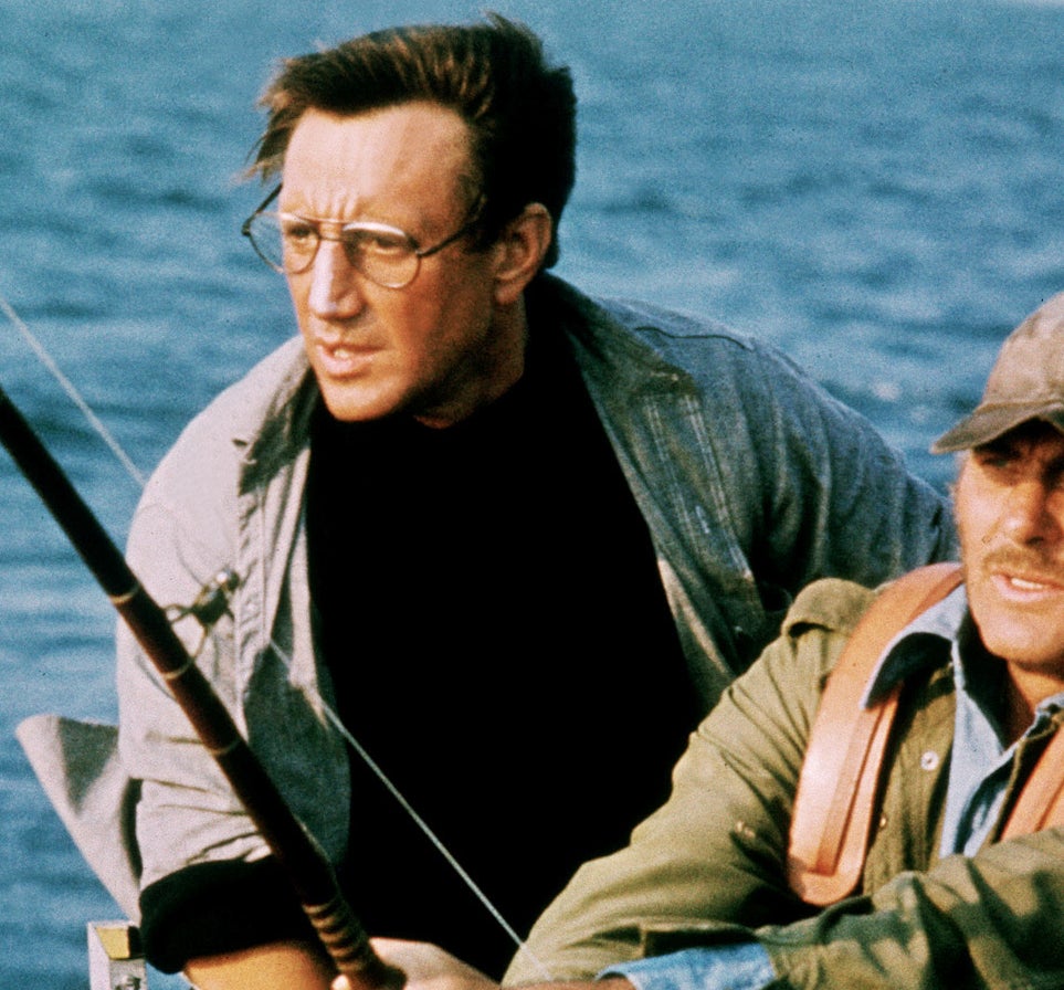 Robert, wearing a jacket and cap, fishing on a boat