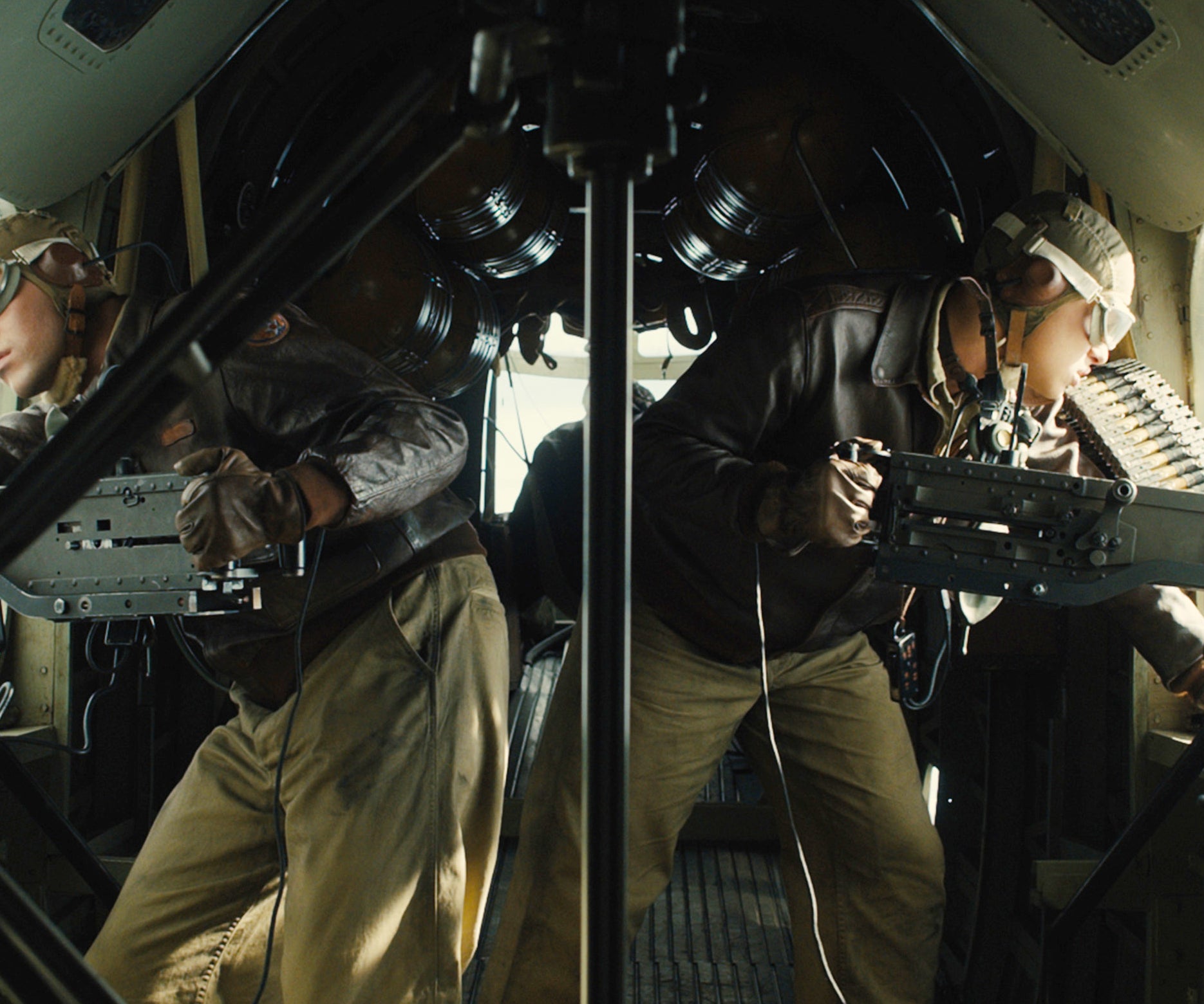 Stephen as a WWII airman operating a machine gun in a bomber aircraft, wearing helmet and goggle, looking out the window intently