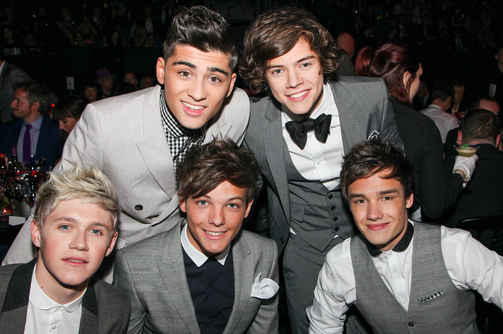 Five men in formal gray suits smiling at a social event