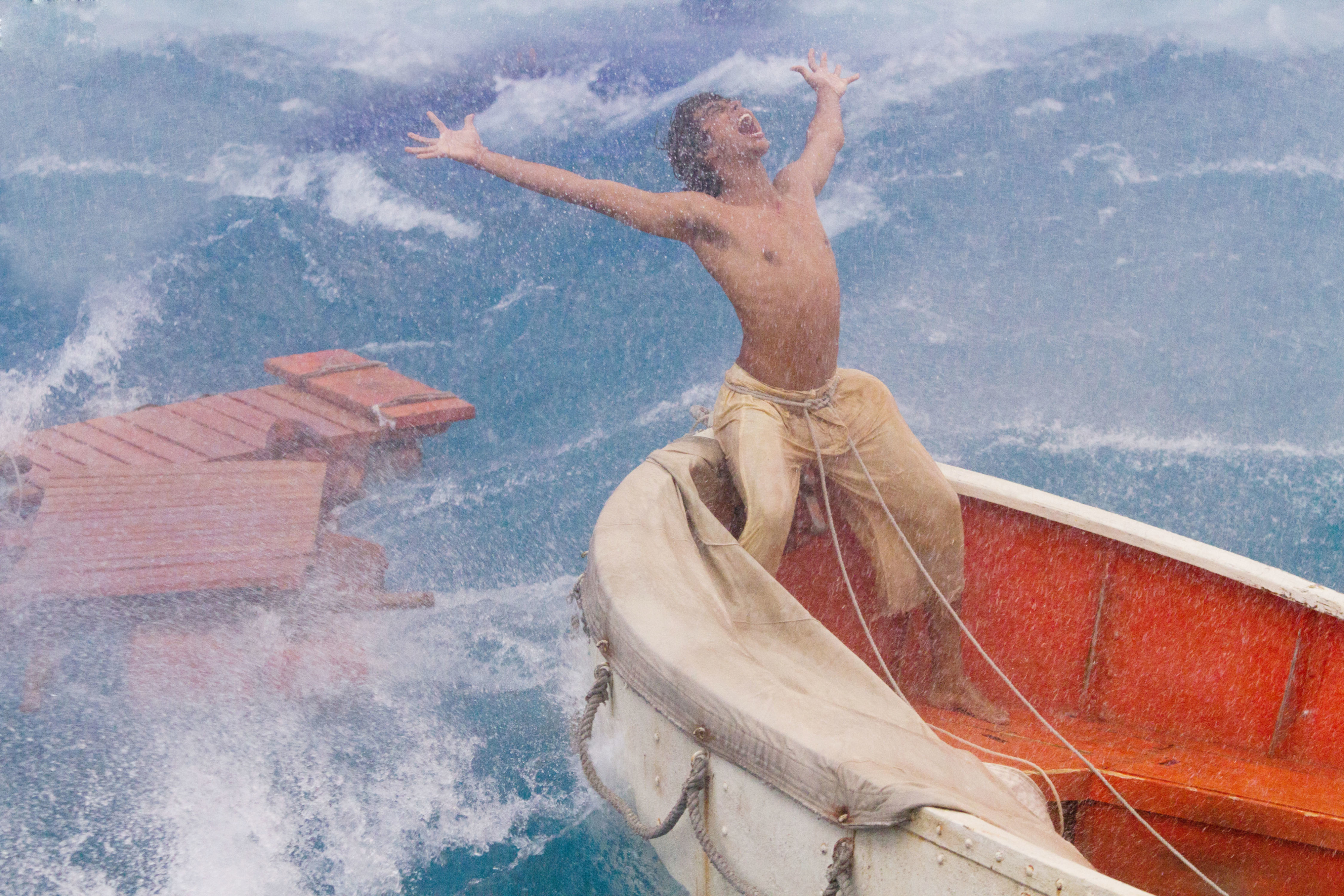 A person stands triumphantly on a lifeboat during a stormy sea in a scene from &quot;Life of Pi.&quot;