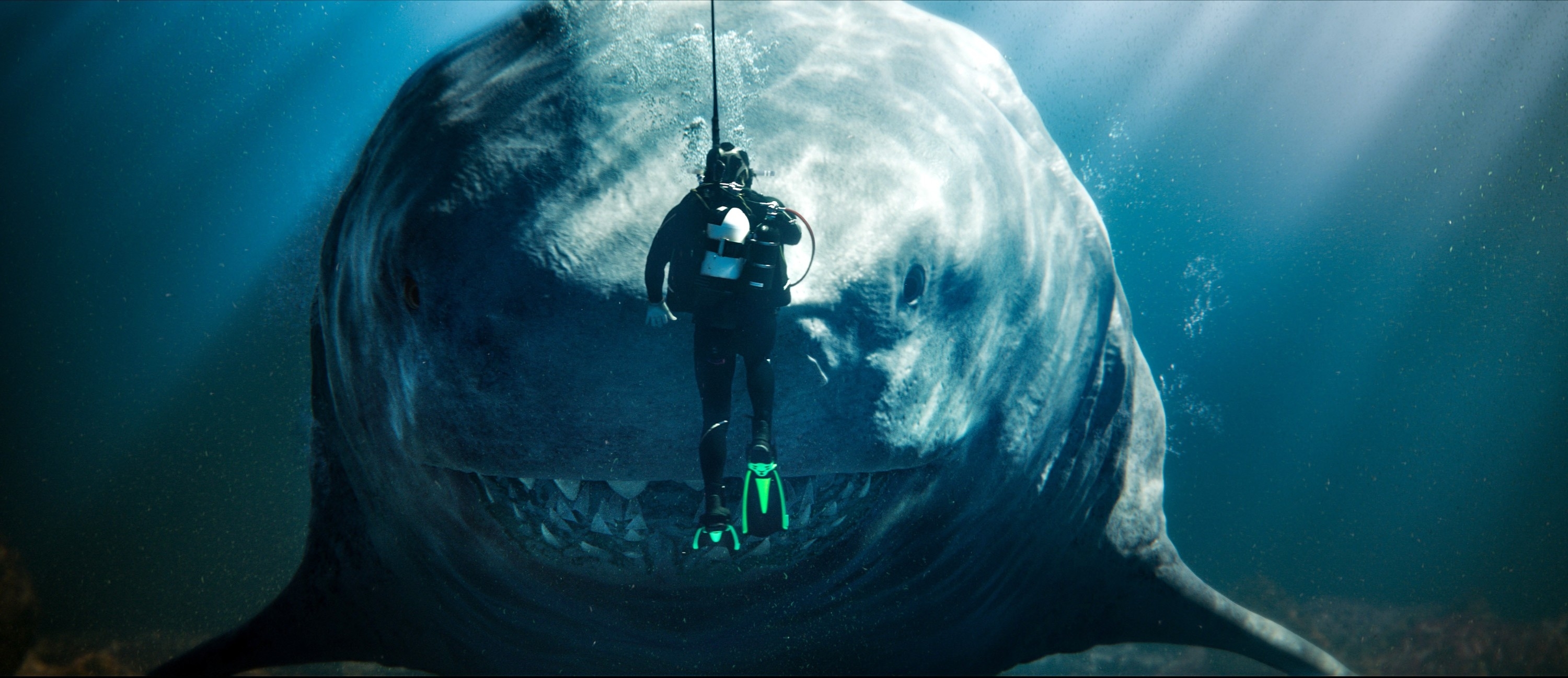 A diver is swimming near a large shark underwater, appearing from a movie scene